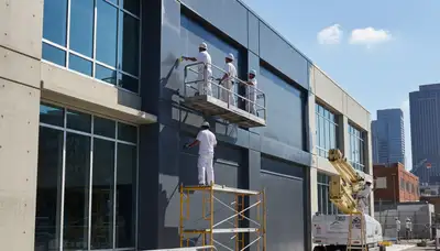 Professional commercial painters in Bloomington IN applying durable exterior paint to business building